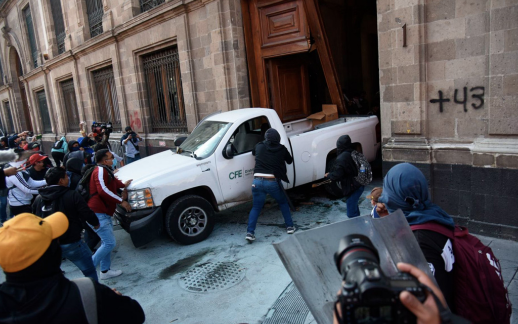Puerta de Palacio Nacional, patrimonio cultural de México, es derribada por normalistas; INAH anuncia proyecto de restauración